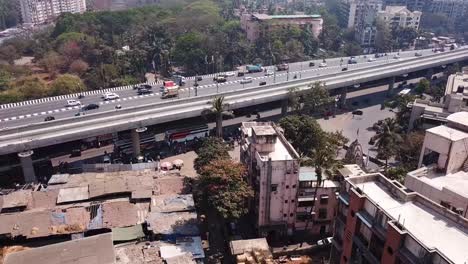 Aerial-Shot-of-Slums-on-a-Hot-Day-in-Mumbai,-India-with-Highway-in-the-background