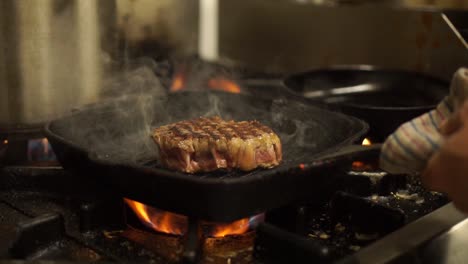 close up - chef putting a bbq grill pan with a steak into the oven