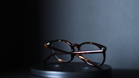 brown and green tortoiseshell round prescription glasses rotating 360 degrees against a black background