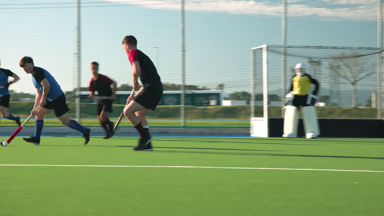 Playing field hockey, male athletes competing in intense match on green field