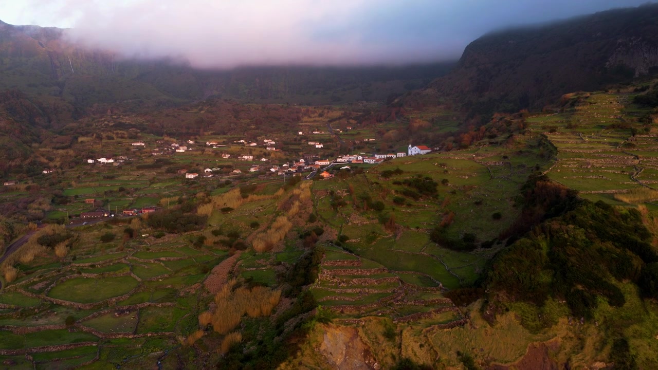 Piccolo villaggio costiero di Fajãzinha sull'isola di Flores nelle Azzorre, Portogallo, con il paesaggio costiero circostante. Ripresa aerea in avanti