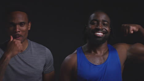 Retrato-De-Estudio-De-Amigos-Atléticos-Sonrientes-En-Ropa-Deportiva-Entrenando-Y-Chocando-Los-Puños-Contra-Un-Fondo-Negro-1