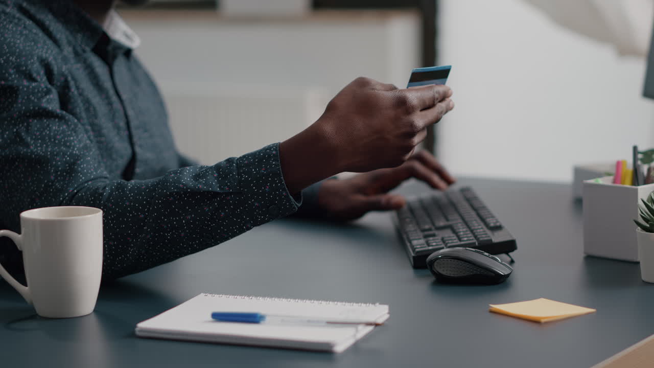 Close up of african american man hands typing credit card info on computer keyborad