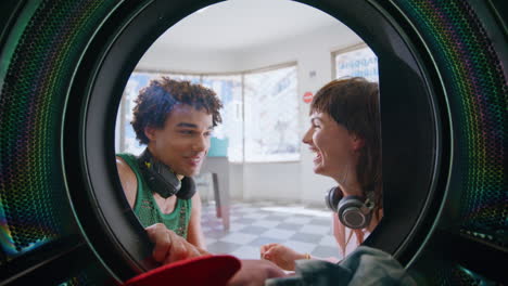 laundry girl talking guy in self service closeup. joyful teen couple enjoying