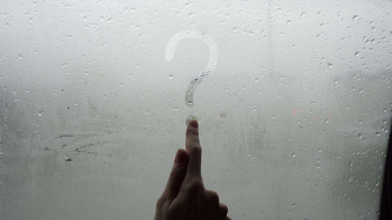 Female hand draws a question mark on the misted glass.