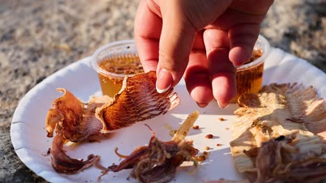 hand picking grilled food from a plate