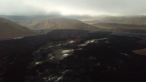 Aerial-landscape-view-of-Meradalir-valley,-Iceland,-with-Fagradalsfjall-volcano-erupting-in-the-distance