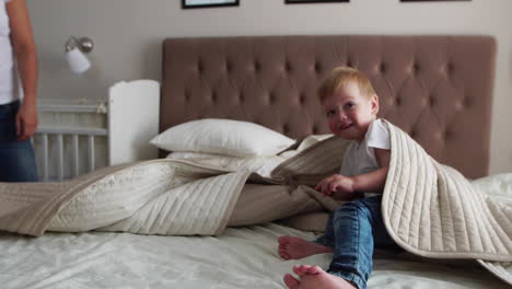 Young-mother-and-father-with-her-2-years-old-little-son-dressed-in-pajamas-are-relaxing-and-playing-in-the-bed-at-the-weekend-together,-lazy-morning,-warm-and-cozy-scene.-Pastel-colors,-selective-focus