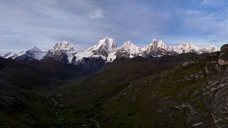 cinematic aerial view of snowy andes mountains in peru with glaciers, rocky cliffs, and hidden blue alpine lake under misty clouds, dramatic landscape and natural travel destination