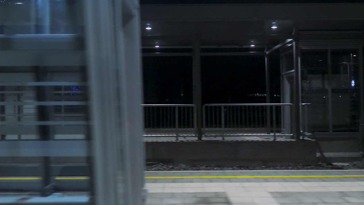 vista de los pasajeros desde el interior del tren que pasa por la estación de tren por la noche.