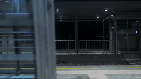 passenger view from inside of the train passing train station at night