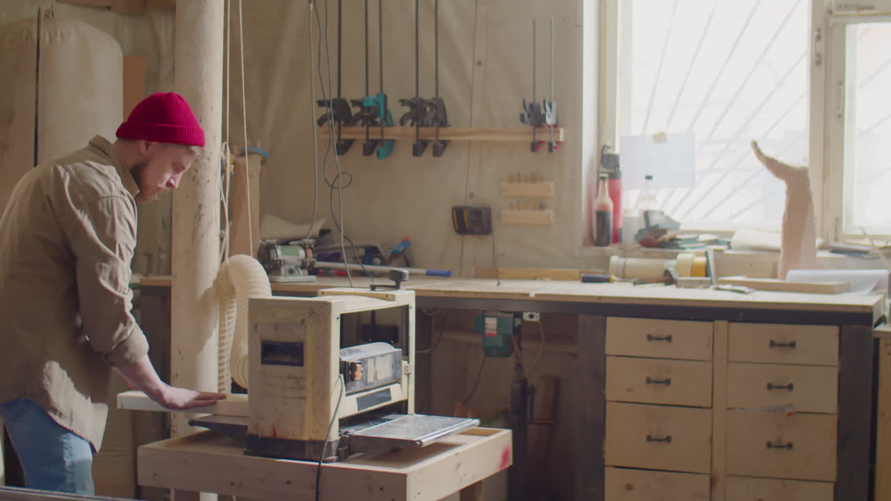 Woodworker Using Thickness Planer in Workshop