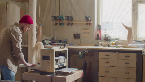 woodworker using thickness planer in workshop