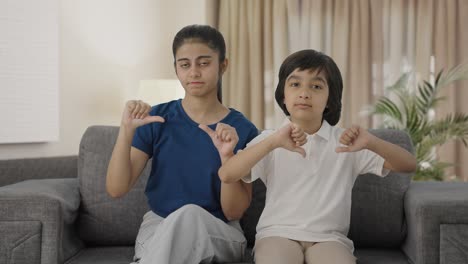 indian siblings showing thumbs down to the camera