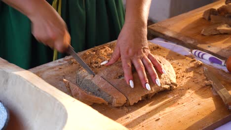 a person slices homemade bread on a wooden cutting board with a knife