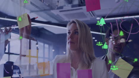 animation of network of media icons over caucasian male and female colleague brainstorming at office