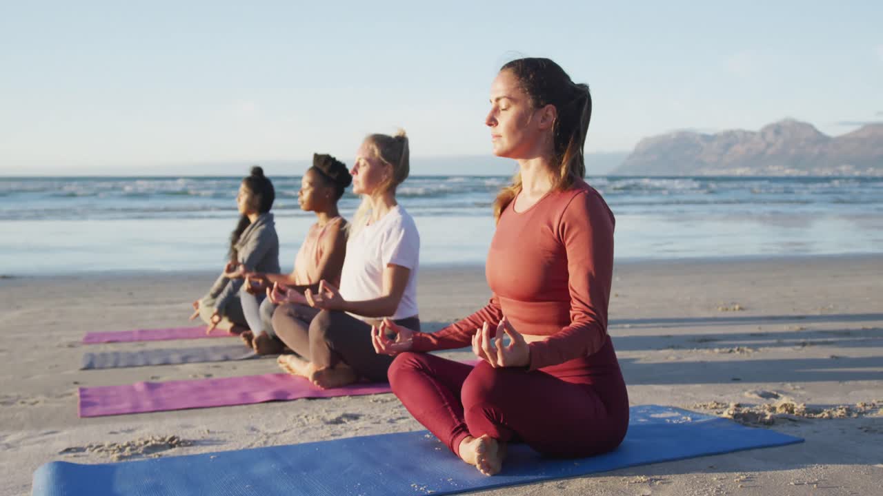 grupo de diversas amigas meditando en la playa