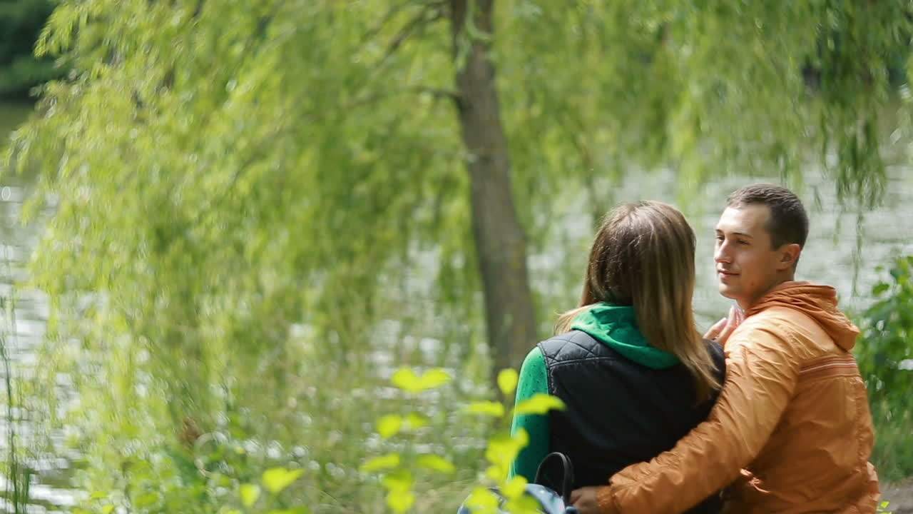 Romantic Couple On Bench. Loving young couple flirting while sitting at a park bench