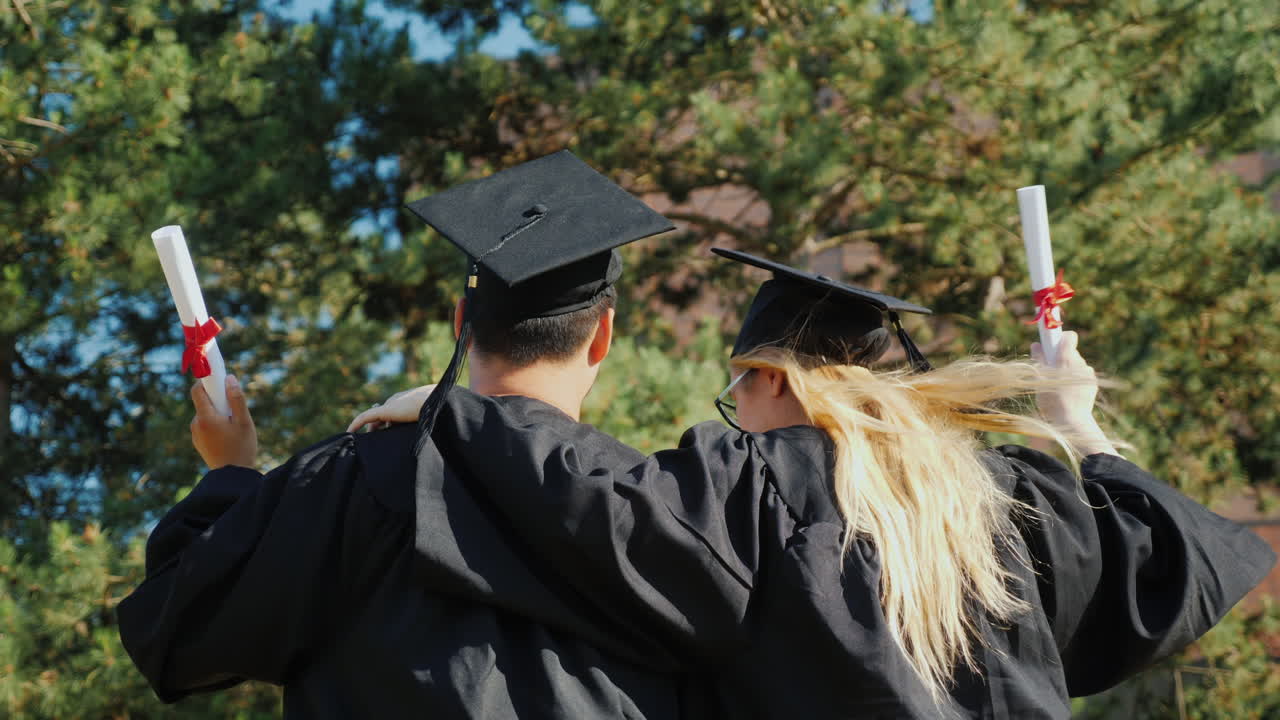 los graduados se felicitan por graduarse de la universidad abrazándose