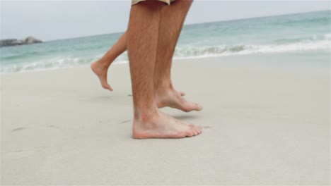 Low-section-of-couple-walking-barefoot-on-the-beach-4k