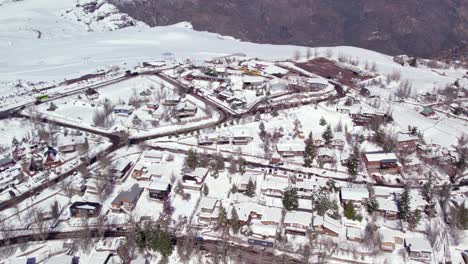 Aerial-view-establishing-the-mountain-village-of-Farellones-with-European-style-chalets-and-cabins,-full-of-snow,-Chile's-tourist-attraction