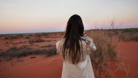 una mujer está tomando fotos con su teléfono mientras está de pie en el amplio desierto de namibia