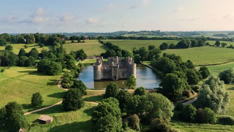 stunning aerial drone footage of bodiam castle as the camera flies away from rear of castle, offering a dramatic, sweeping view. ideal for cinematic, historical, and travel content.