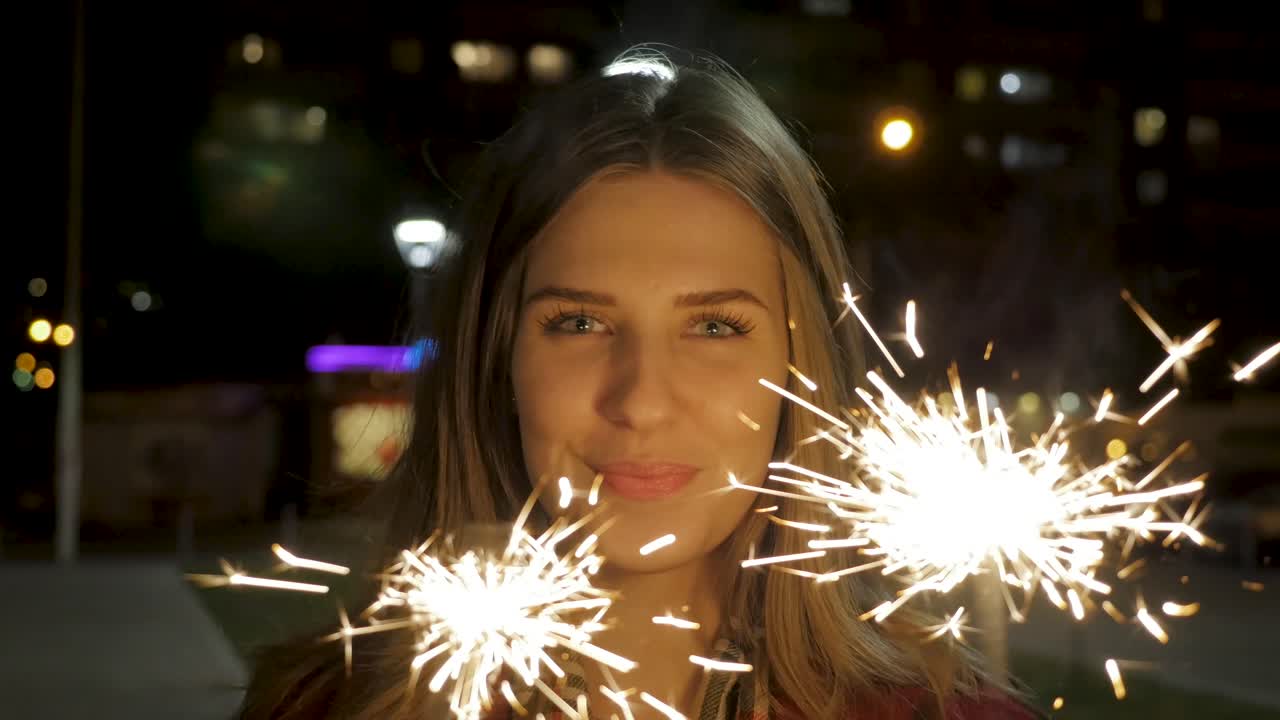 mujer celebrando por la noche con chispas