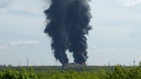 a giant fire and a column of black smoke after the explosion at the oil storage