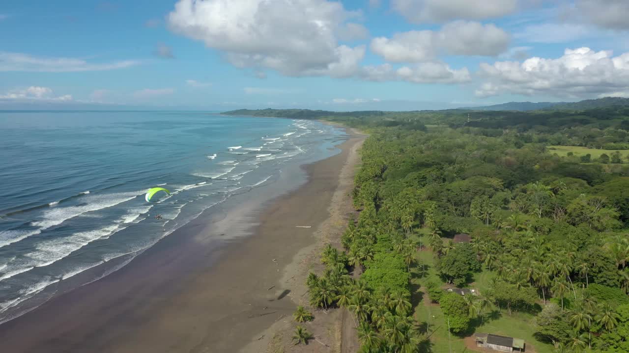 un parapente sobrevolando una playa y un bosque en la costa de costa rica