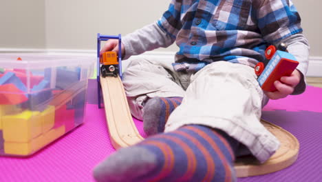 Toddler-boy-playing-with-a-wooden-toy-train-set