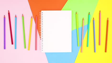 colored pencils move on left and right side of open notebook. stop motion