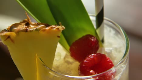 close up of pina colada cocktail on table, with raspberries and pineapple