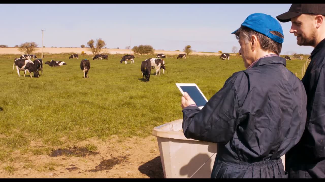 dos ganaderos interactuando entre sí mientras usan una tableta digital