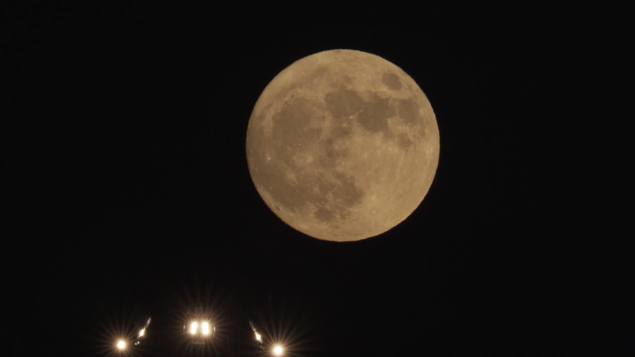 An airliner passes in front of a full moon on approach to landing at Los Angeles International Airport.