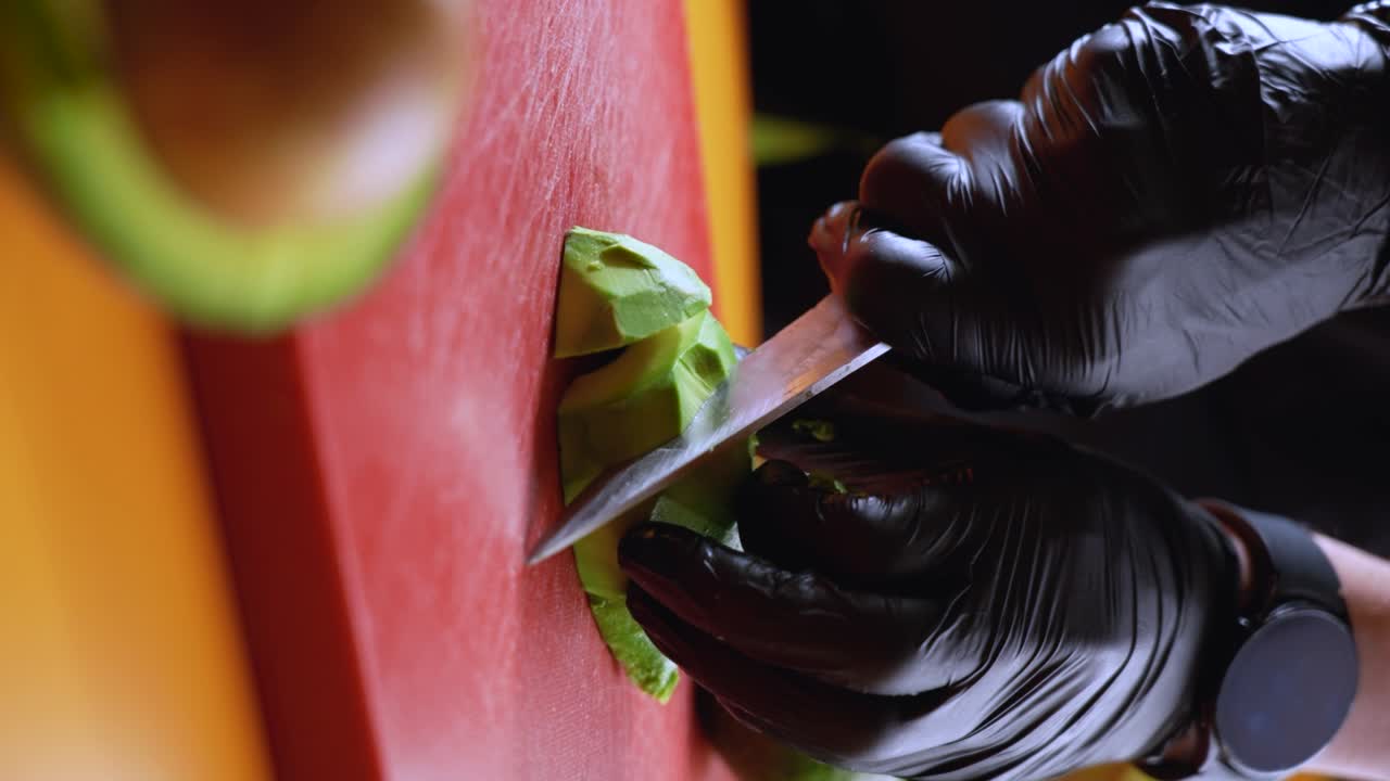 el chef corta un aguacate en una tabla de cortar roja