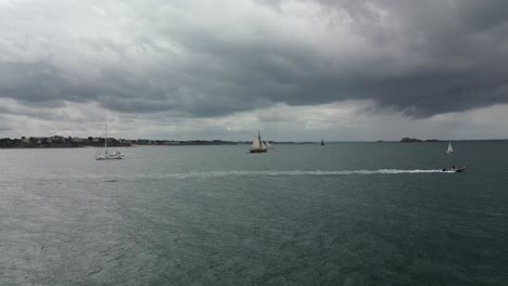 Drohne-Fliegt-In-Richtung-Le-Renard-Robert-Surcouf-Holzboot-Auf-Dem-Meer-Mit-Bewölktem-Himmel