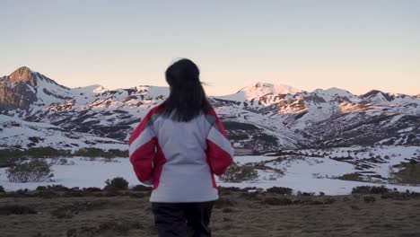 一个女人在冬季慢动作地走向一系列被雪覆盖的山脉