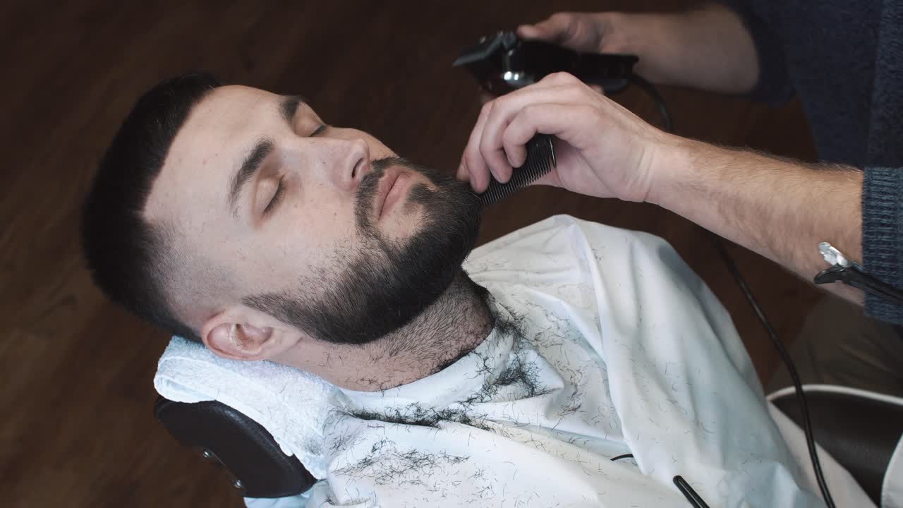 Mand får trimmet skæg hos en barbershop