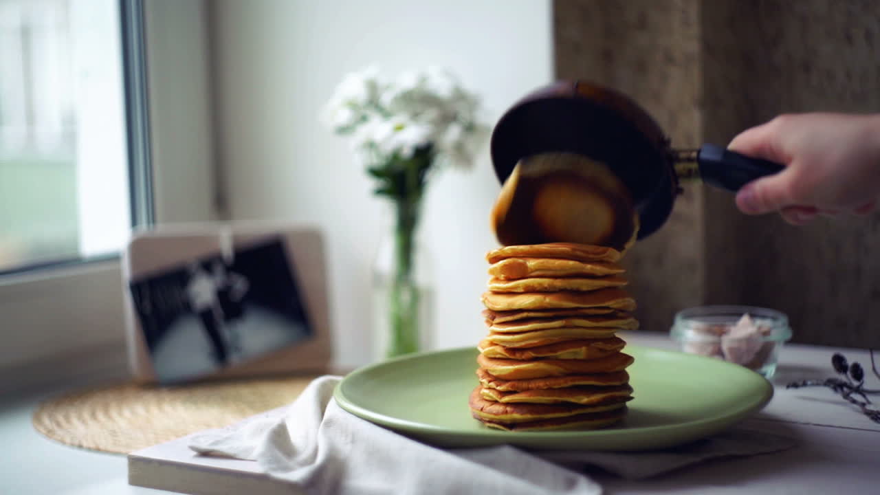 mujer pone panqueque de la sartén de panqueque en la parte superior de la pila de panqueque. panqueques desayuno