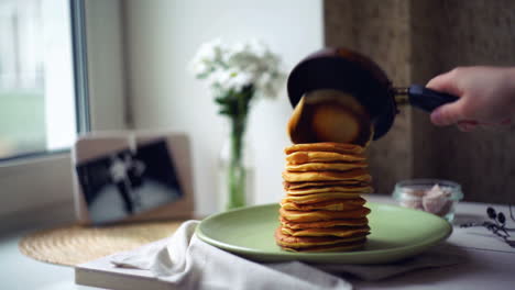 woman puts pancake from pancake pan on top of pancake stack. pancakes breakfast