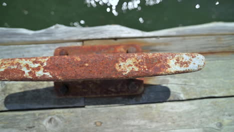 old metal cleat on wooden dock to tie boats up - close up, slider right