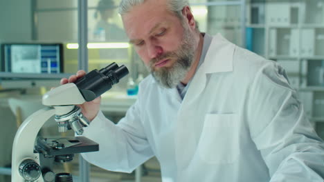 senior scientist using microscope in lab