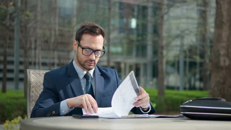 business man turn pages with notes on clipboard in a park