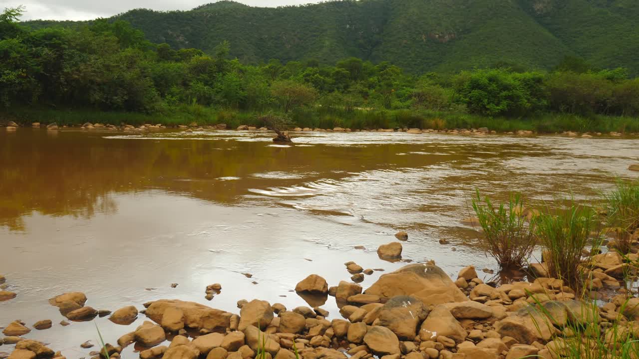 río pongola fangoso que fluye lentamente a través del paisaje montañoso africano con un fondo exuberante y tupido
