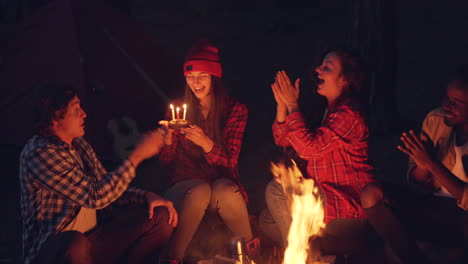 friends celebrating birthday around campfire