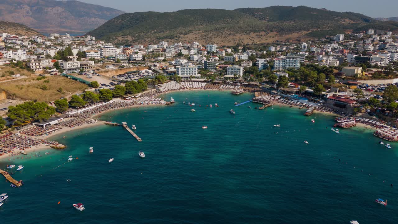 Ksamil beach, showing clear water, boats, and a vibrant coastal town., aerial view