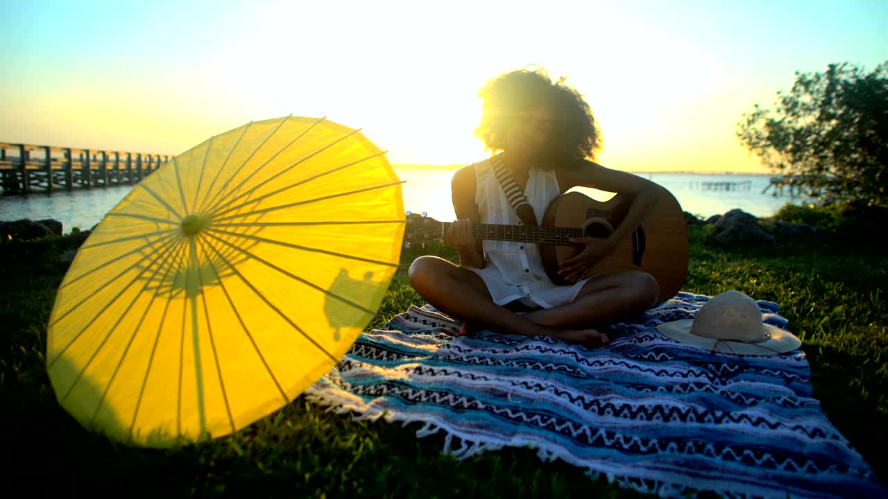 mujer afroamericana tocando la guitarra en un picnic en la playa
