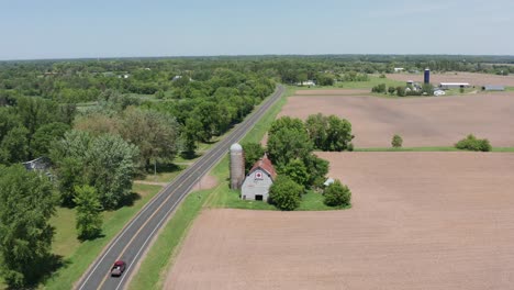 aerial wide descending shot of an old barn and silo in the rural farmland of minnesota