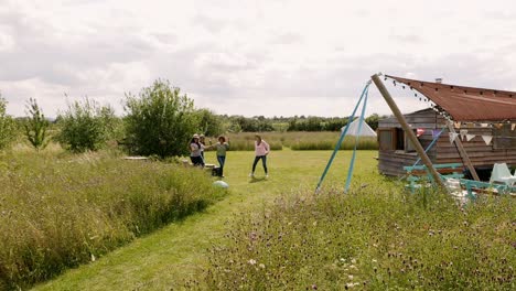 drone shot of group of mature friends walking along path through yurt campsite